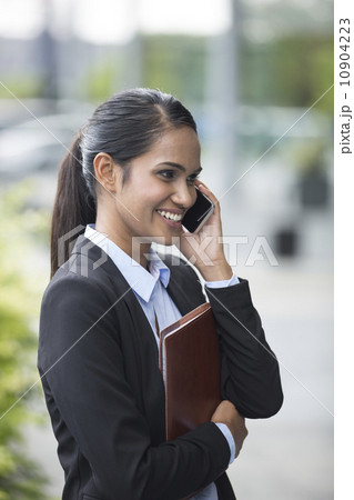 Young Indian businesswoman standing outside using mobile phone 10904223