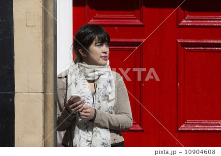 Trendy Asian woman standing by a red door. 10904608