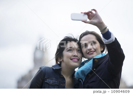 Caucasian and Chinese friends taking photo with phone. Caucasian and Chinese friends taking photo with phone. 10904609