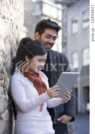 Asian friends sitting outdoors using digital Tablet. Asian friends sitting outdoors using digital Tablet. 10904631