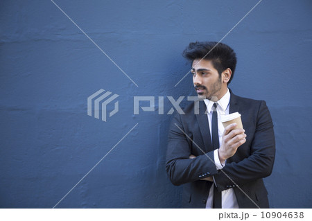 Indian businessman leaning against a stone wall. 10904638