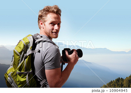 Young man taking photo on top of mountain Young man taking photo on top of mountain 10904945