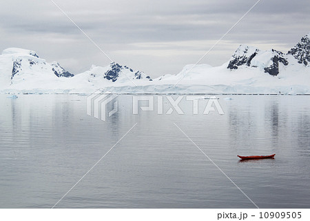 A small boat, a kayak on the flat calm waters off an Antarctic island shore. 10909505