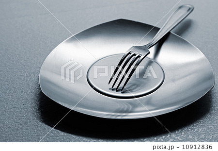 Empty steel plate with fork on the table. Monochrome photo with shallow depth of field Empty steel plate with fork on the table. Monochrome photo with shallow depth of field 10912836