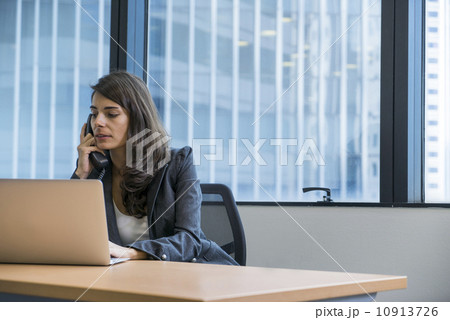 Asian executive in a jacket making a call in the office. Asian executive in a jacket making a call in the office. 10913726