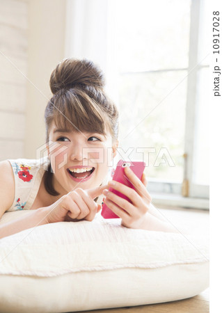 寝転んでスマホを操作する女性の写真素材