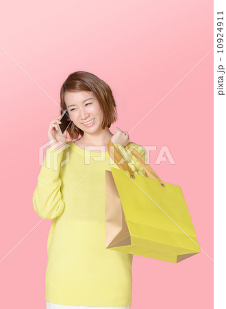 買い物袋をもって電話する女性 買い物袋をもって電話する女性 10924911