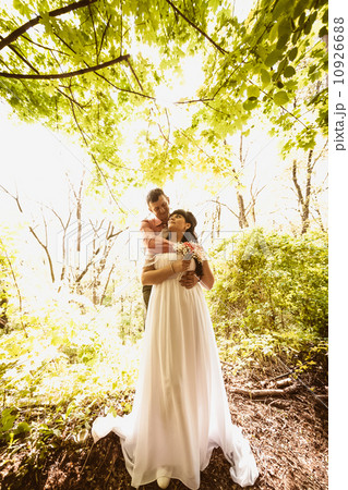 Toned photo of beautiful newly married couple hugging under tree Toned photo of beautiful newly married couple hugging under tree 10926688