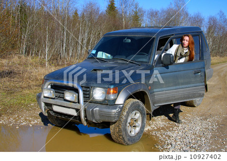 Young woman behind rudder of offroad car on dirt road before water obstacle Young woman behind rudder of offroad car on dirt road before water obstacle 10927402