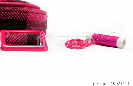 Reel of thread with a needle, buttons and a belt on a white back Reel of thread with a needle, buttons and a belt on a white back 10928511
