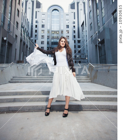 Woman in long white dress with veil standing against urban build Woman in long white dress with veil standing against urban build 10930635