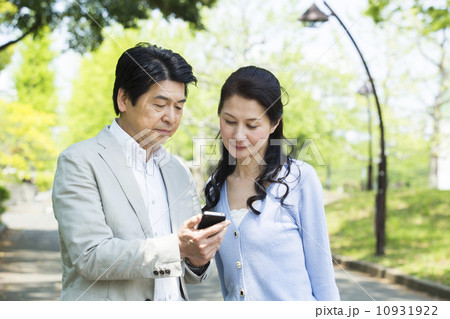 屋外でスマホを操作するミドル夫婦 屋外でスマホを操作するミドル夫婦 10931922