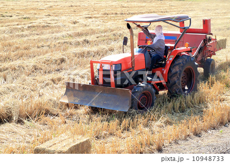 farmer and tractor packing straw in the field at Thailand 10948733
