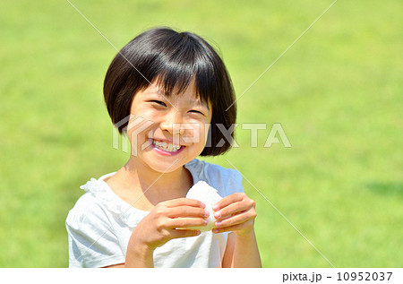 芝生広場でおにぎりを食べる女の子 10952037