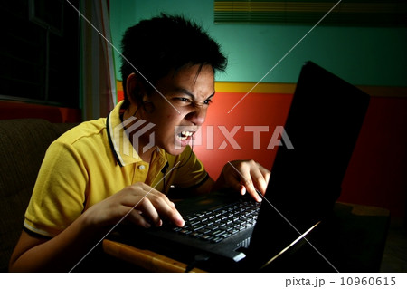Asian Teen Playing or Working on a Laptop Computer 10960615