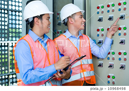 Asian technicians at panel on construction site 10968498