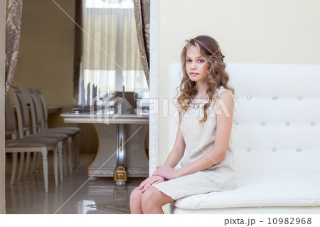 Elegant curly girl sitting on white leather sofa Elegant curly girl sitting on white leather sofa 10982968