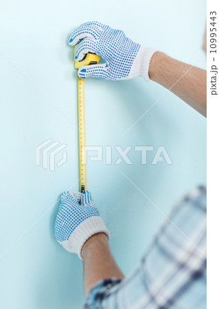 closeup of male in gloves measuring wall with tape closeup of male in gloves measuring wall with tape 10995443