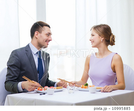 smiling couple eating sushi at restaurant 10995885