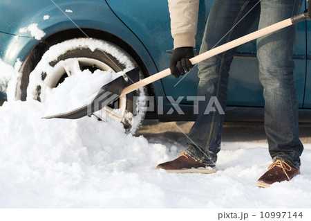 closeup of man digging up stuck in snow car 10997144