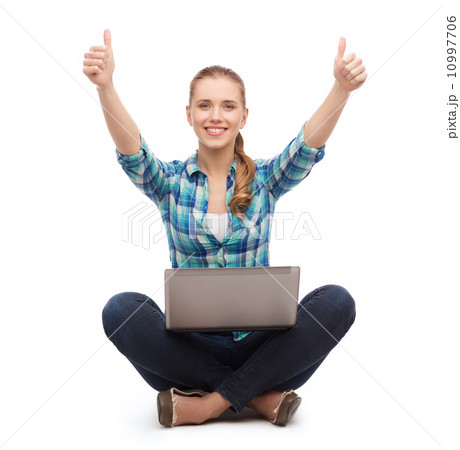 smiling woman with laptop and showing thumbs up 10997706