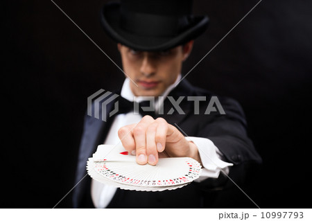 magician in hat showing trick with playing cards 10997793