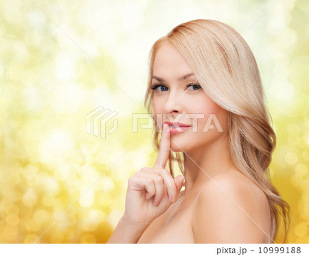 beautiful young woman pointing finger to lips 10999188