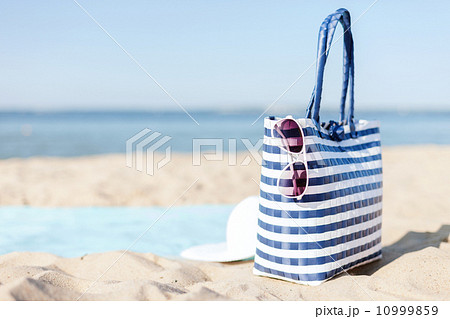 straw hat, sunglasses and bag lying in the sand straw hat, sunglasses and bag lying in the sand 10999859