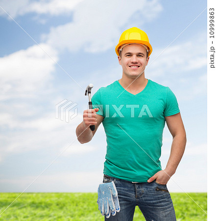 smiling manual worker in helmet with hammer 10999863
