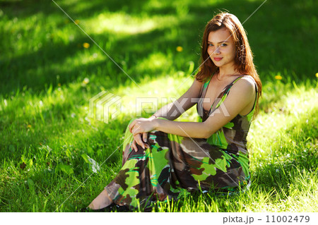 brunette sitting on green grass 11002479
