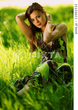 brunette sitting on green grass 11002532