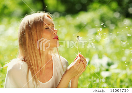 girl blowing on a dandelion 11002730