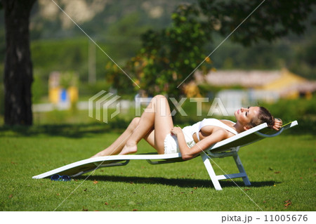 girl sitting in a white lounge on a green grass 11005676