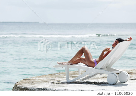 Woman in chaise-lounge near sea 11006020