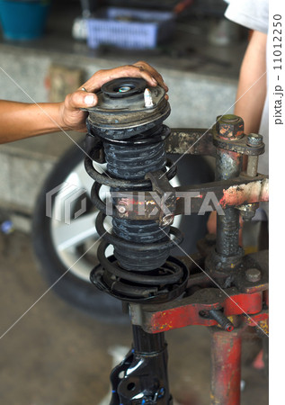 Auto car mechanic working on car shock absorber in car service w Auto car mechanic working on car shock absorber in car service w 11012250