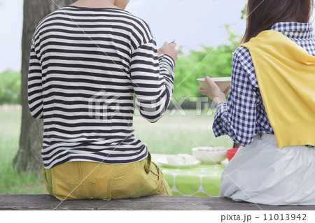 ベンチに座って食事をする男女 11013942