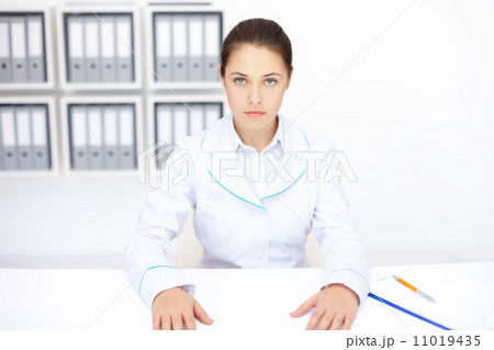 young female doctor sitting at desk in hospital 11019435