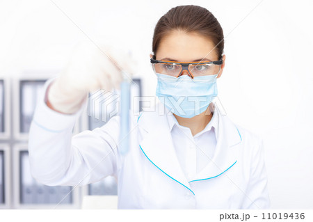 female researcher observing liquid in flask 11019436