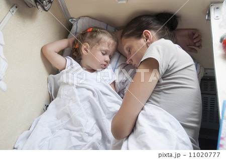 Mother and daughter sleeping on a cot in back of train 11020777