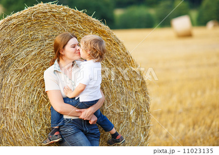 Young mother and her little son having fun on yellow hay field 11023135