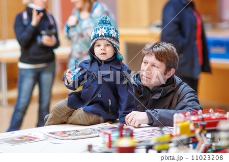 Father and  little son having fun on toy exposition, indoors. 11023208