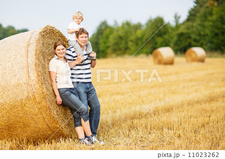 happy family of three on yellow hay field in summer. 11023262