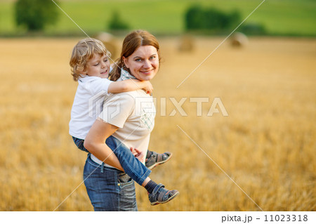 Young mother and her little son having fun on yellow hay field 11023318