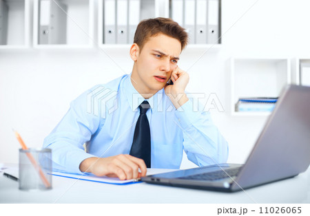 Young pensive businessman talking on cell phone 11026065