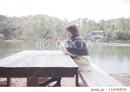 公園のテーブルで携帯をさわるニットセーターを着た女性 公園のテーブルで携帯をさわるニットセーターを着た女性 11046650