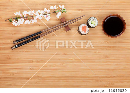 Sushi maki with fresh sakura branch over bamboo table 11056029