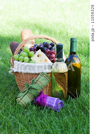 Outdoor picnic basket with wine on lawn 11056326