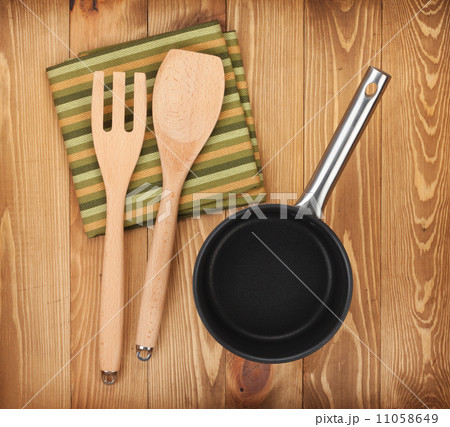 Frying pan and kitchen utensils on wooden table 11058649