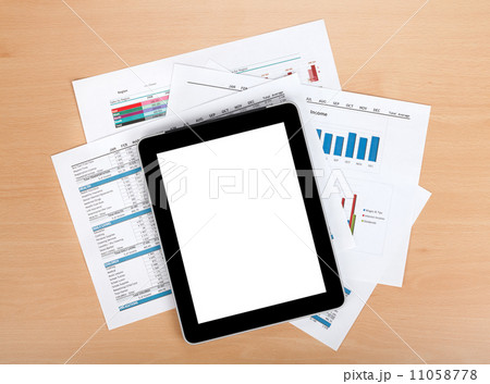 Tablet with blank screen over papers with numbers and charts 11058778