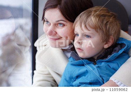 Mother and toddler son looking out train window outside Mother and toddler son looking out train window outside 11059062